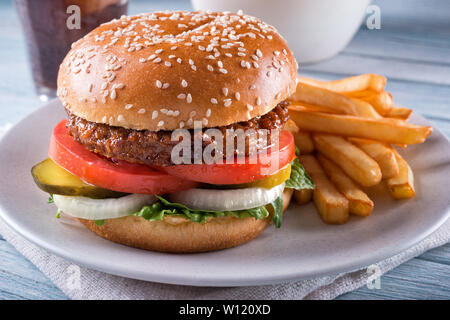 A beyond delicious plant based non meat burger with lettuce, onion, pickle, tomato and french fries. Stock Photo