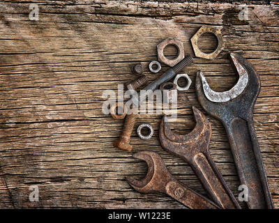 Old wrenches on the nuts and bolts on a wooden grungy background Stock Photo