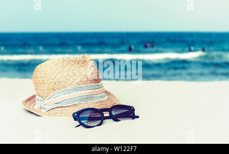 Vintage wicker straw hat and black sun glasses on a tropical beach, summer concept Stock Photo