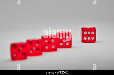 Red dice on a grey background with one die in sharp focus showing six, symbolizing chance, luck and probability. Stock Photo