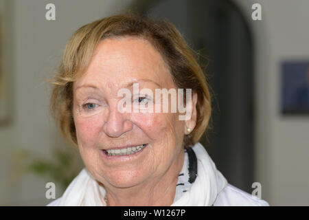 Senior attractive woman with blond hair wearing a scarf in a close up candid portrait indoors at home Stock Photo