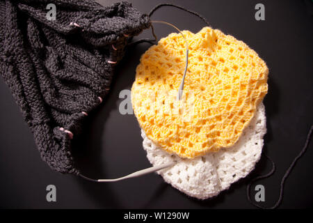 Lay flat view of two bright coloured hats and a grey knitted blanket, all projects hand made Stock Photo