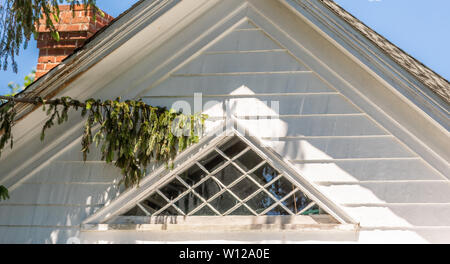 Triangle shaped window on the third floor of an old Sag Harbor home Stock Photo