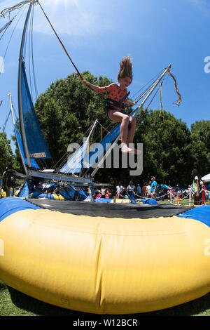 A girl gets airborne bouncing on a bungee trampoline at the Atlanta Ice Cream Festival in Piedmont Park on July 28, 2018 in Atlanta, GA. Stock Photo