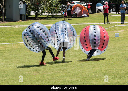 Teenage boys wearing plastic zorbs bump into each other and knock each other down at the Atlanta Ice Cream Festival on July 28, 2018 in Atlanta, GA. Stock Photo