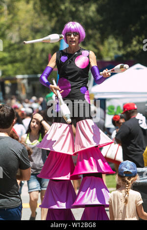 A female walking on stilts juggles for the patrons attending the annual Atlanta Ice Cream Festival on July 28, 2018 in Atlanta, GA. Stock Photo