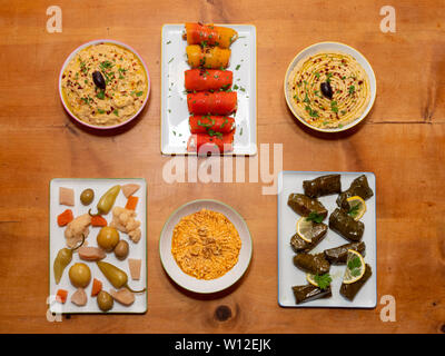 Meze Assorted Turkish Starters on a Wooden Table - Stuffed Vine Leaves, Pepper Rolls, Pickles, Hummus, Babaganoush - Turkish Cuisine Stock Photo