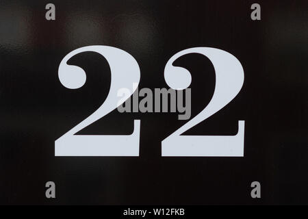 House number 22 in white curled lettering on a black shiny surface Stock Photo