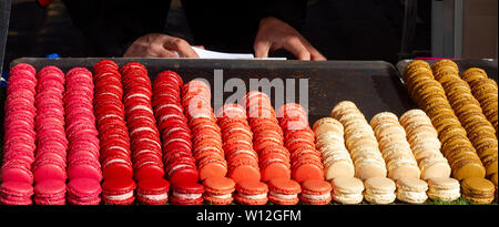 Fresh macarons arranged in colorful columns and rows, sorted precisely on a market stand Stock Photo