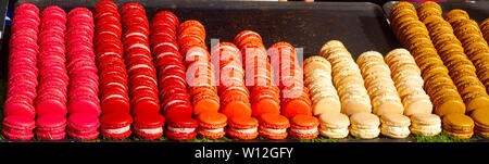 Fresh macarons arranged in colorful columns and rows, sorted precisely on a market stand Stock Photo
