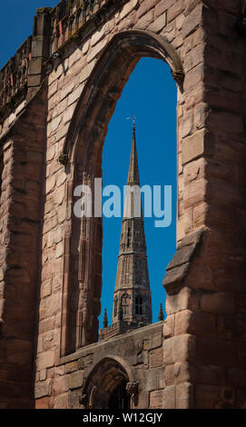 Coventry, Warwickshire, United Kingsom, June 27th 2019, spire of Holy Trinity Church seen through a ruined window of Saint Michaels Cathedral Stock Photo