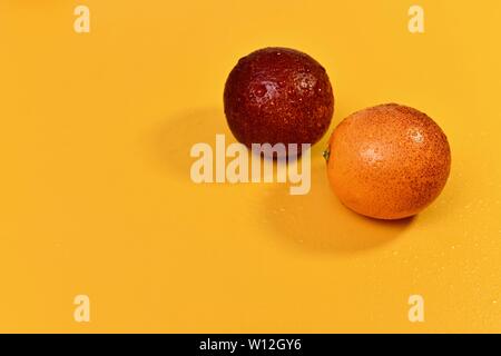 Two red round oranges, wet from water, with shadows 7a a yellow background. On the right, above. Stock Photo