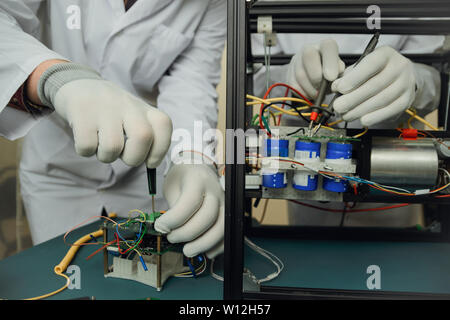 workers in gloves assemble an electrical circuit and measure the voltage Stock Photo