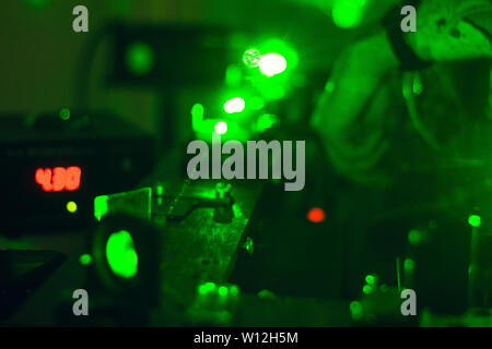 Scientist with glass demonstrates microparticle laser, green laser science research Stock Photo