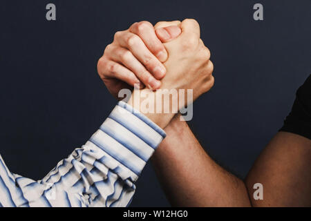 Closeup of two businessmen competing in arm wrestling on a dark blue background. challenge, competition and rivalry concept - close up of male friends Stock Photo