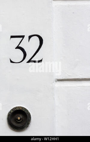 House number 32 with the thirty-two painted in black on a white wall Stock Photo