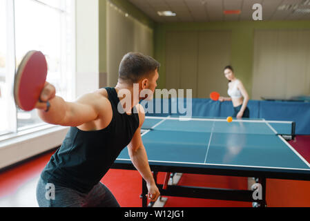 Man and woman playing ping pong, focus on racket Stock Photo
