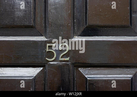 House number 52 with the fifty-two in metal digits on a black painted old wooden front door Stock Photo