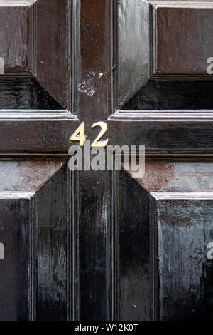 House number 42 with the forty-two in metal digits on a black painted old wooden front door
