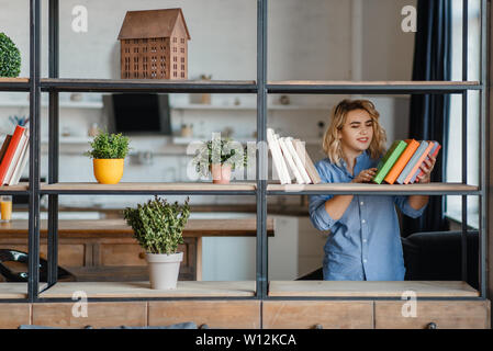 Young woman sprays home plants on the shelf Stock Photo