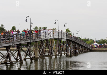 Annapolis, Maryland, USA. 22nd May, 2019. A crowd of spectators, military personnel, and cadets stream from Forrest Sherman Field and cross the pedestrian Fitch Bridge, over Dorsey Creek, as they depart after an air show by the Blue Angels, the U.S. Navy's flight demonstration squadron, during Commissioning Week 2019 at the United States Naval Academy (USNA). Kay Howell/Alamy Stock Photo