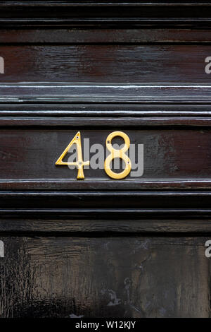 House number 48 with the forty-eight in metal digits on a black painted old wooden front door Stock Photo