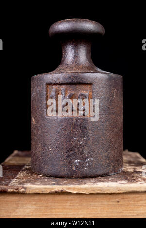 Old kilo weights on books. Old books and weighing machines. Dark background. Stock Photo