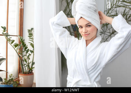 Young woman rest at home beauty care standing wearing towel fixing looking camera smiling joyful Stock Photo