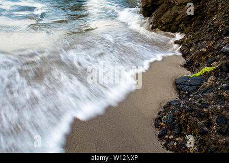 Waves crashing on the rocks at Wood’s Cove in Laguna Beach, California. Slow shutter speed. Stock Photo