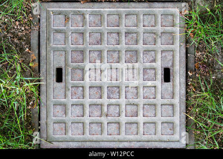 A small squared manhole cover with a rectangular pattern as found in the Grosser Garten at Dresden. It shows two rectangular openings to facilitate th Stock Photo