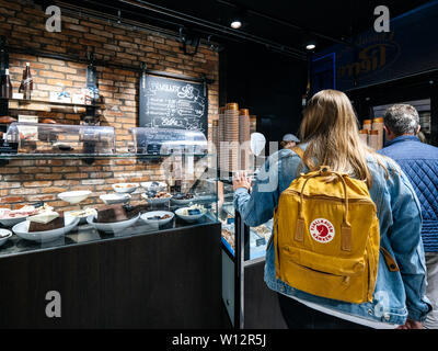 Haarlem, Netherlands - Aug 15, 2018: Rear view of young Dutch woman with FjallRaven backpack waiting in traditional dutch bakery to buy sweets