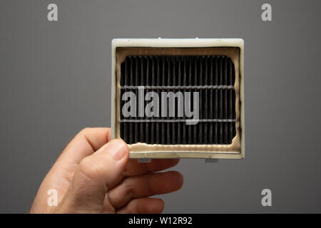 Man hand holding vacuum hepa filter in hand full with dust black with microbes and allergies Stock Photo