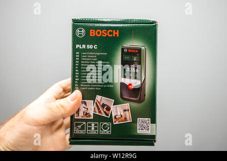 Paris, France - Jun 4, 2019: Man hand holding Bosch PLR 50 C laser measure cardboard packaging box in hand Stock Photo