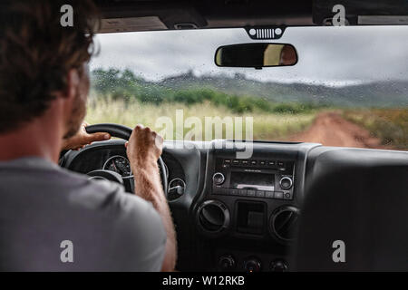Man driver driving off road trail path with 4x4 car on adventure trip travel holiday. Hawaii drive in the rain bad weather. Stock Photo