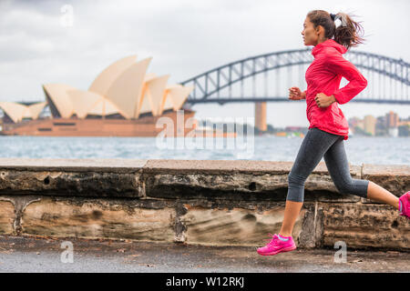 Runner fit active lifestyle woman jogging on Sydney Harbour by the Opera house famous tourist attraction landmark. City life. Stock Photo