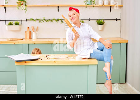 Portrait of smiling young housewife with rolling pin Stock Photo