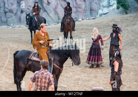 Hamburg, Germany. 29th June, 2019. The actor Sascha Gluth as Old Shatterhand sits on his horse in the open-air theatre at Kalkberg during the premiere of the play of the Karl May play 'Unter Geiern - Der Sohn des Bärenjägers' ('Among Vultures - The Son of the Bear Hunter'). Around him stand Raul Richter (left) as Martin Baumann, the son of the bear hunter, Larissa Marolt (3rd from left) as Tiffany O Toole and Nicolas König as Hong-peh-te-keh, the heavy moccasin (right). The play premiered in the evening. Credit: Daniel Bockwoldt/dpa/Alamy Live News Stock Photo