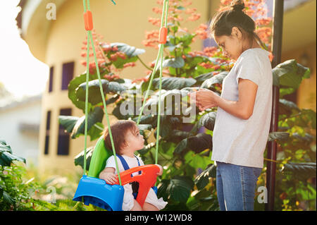 Young nanny looking for baby girl outside of house Stock Photo