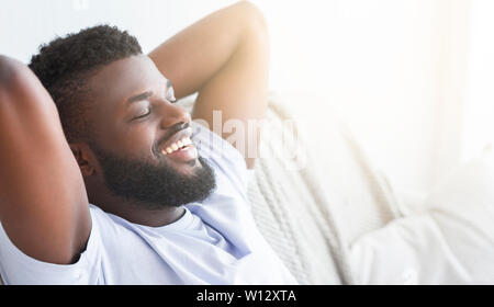 Satisfied black guy relaxing at home, lying with closed eyes Stock Photo