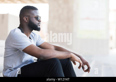 Confident african man in sun glasses sitting outdoor Stock Photo