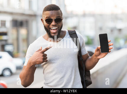 Happy african guy pointing his cellphone with black blank screen Stock Photo