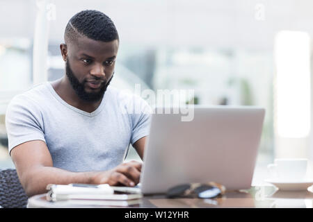 Concentrated young african american guy working on laptop Stock Photo