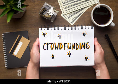 Notepad with crowdfunding concept in woman hands Stock Photo