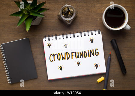 Crowdfunding concept drawing with red pen in notepad Stock Photo