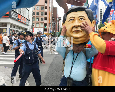 Osaka, Japan. 29th June, 2019. A group of police officers direct the traffic of a protest in Osaka Japan while men wearing costumes pretending in a symbolic way to portrait Japanese Prime Minister Shinzo Abe and Chinese President Xi Jinpin. At the same time the Osaka G20 summit was taking place in the same prefecture. Osaka was the host of the G20 summit that was held on Friday, June 28 and 29. Photo taken on Saturday, June 29, 2019. Photo by: Ramiro AgustÃ-n Vargas Tabares Credit: Ramiro Agustin Vargas Tabares/ZUMA Wire/Alamy Live News Stock Photo