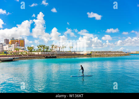 man doing paddle surfing in the Hamakawa fishing port in the vicinity of the American Village in Chatan City of Okinawa. Stock Photo