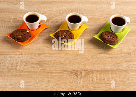 Tabletop perspective on three cups of espresso and chocolate biscuits Stock Photo