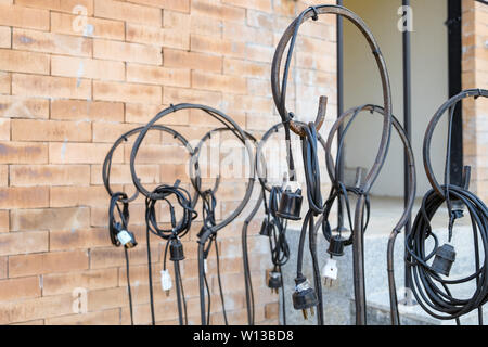 Black wire and plug hanging on steel pole side brick wall Stock Photo