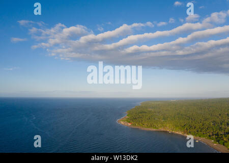 Coast island Camiguin, view from above. Beach with volcanic sand. Seascape, island with dense tropical forest. Stock Photo