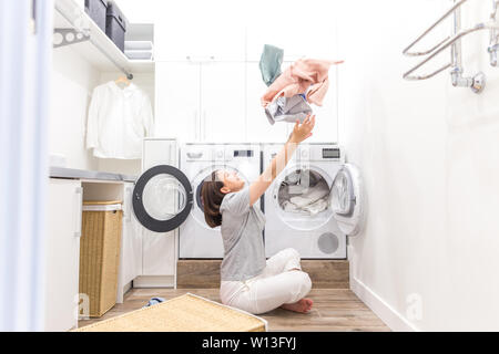 Happy family mother housewife in laundry room with washing machine throwing clothes up Stock Photo